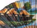 a fan with a painting of a village on it