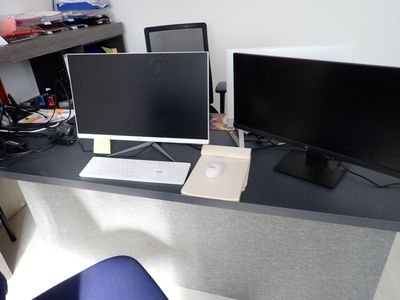un bureau sur lequel sont posés deux écrans et un ordinateur portable