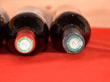 three bottles of wine are lined up on a red cloth