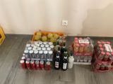 Des bouteilles et des canettes de soda sont posées par terre près d'un mur.