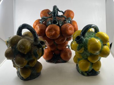 three ceramic figurines of fruits and vegetables in a display case
