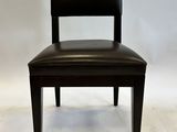 the back of a black leather chair against a white backdrop