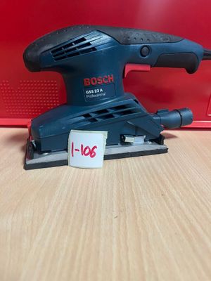 une ponceuse orbitale Bosch posée sur une table, à côté d'une boîte rouge