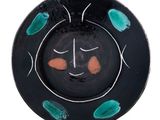 une assiette noire ornée de motifs verts et orange