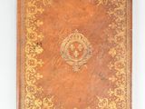 an old book with a gold cover on a white surface