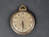 une montre de poche en or posée sur une table, sur fond noir