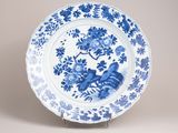 assiette bleue et blanche ornée de fleurs, posée sur un socle