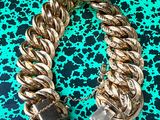 un gros plan d'un bracelet en chaîne dorée posé sur une surface verte