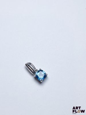 On voit l'image d'une topaze bleue posée sur une surface blanche.