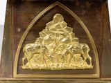 a gold plated clock on a wooden stand