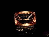 a close up of a ring with an orange diamond on a black surface