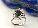 une image représentant une bague sertie d'un diamant noir posée sur une pierre bleue