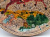 a plate with a painting of a man riding a horse on it