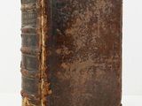an old book sitting on top of a white table next to a white wall