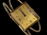 une image d'une montre en or avec des chiffres romains sur le cadran