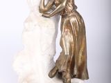 statue représentant une femme en train d'enlacer un homme, assis sur un rocher, sur fond blanc