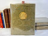 a book with a gold medallion on it next to a stack of books