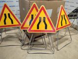 three road signs that are on a stand in front of a cardboard box