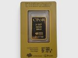 un lingot d'or dans un emballage posé sur une surface blanche