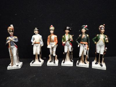 cinq figurines représentant des hommes en uniforme militaire sont alignées sur une surface noire