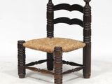 une image représentant une chaise en bois avec une assise tressée, posée sur une surface blanche