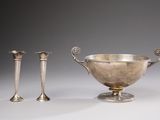 two silver vases and two candles on a white surface