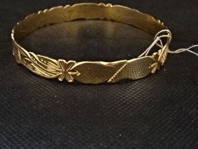 gros plan d'un bracelet en or sur une surface noire