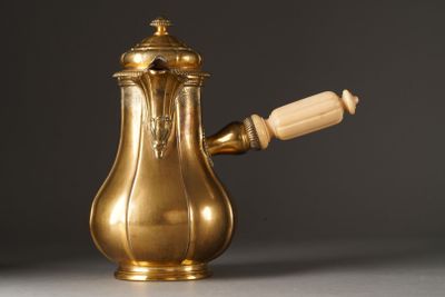 an antique brass coffee pot with a wooden handle on a table