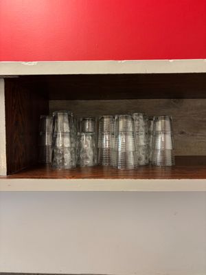 bottles and glasses are lined up on a shelf against a red wall