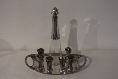 un plateau en argent sur lequel sont posés une bouteille et quatre verres