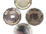 trois plats plaqués argent sur un fond blanc, avec un miroir au centre