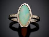 une bague en oplite blanche sertie d'un diamant, posée sur un fond noir