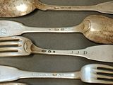 five forks and two spoons that are on a table