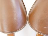 the back of a pair of brown leather shoes with white stitching