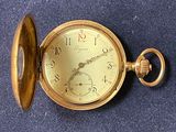a gold pocket watch sitting on a blue surface