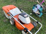 an orange and white lawn mower sitting on top of a lush green field