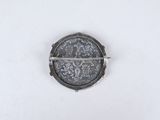 a close up of a coin on a white surface with a small piece of metal in the middle