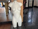 un mannequin blanc au milieu d'un sol carrelé noir