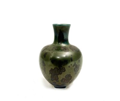 un vase vert posé sur une surface blanche