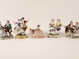 a group of six figurines of people sitting on a white surface