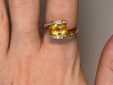 a woman ' s hand holding a yellow and white diamond ring