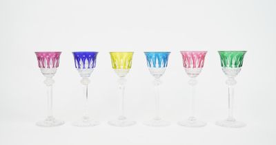 six colorful wine glasses lined up in a row on a white surface