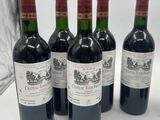four bottles of wine are lined up on a white surface