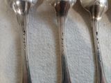 trois cuillères en argent posées sur une nappe blanche