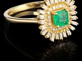 une bague en émeraude et diamant sur une surface noire