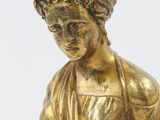 a gold statue of a woman sitting on a rock with her hands in her pockets