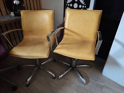 pair of yellow leather office chairs with chrome steel legs