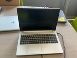 an open laptop computer sitting on top of a wooden table next to a green chair