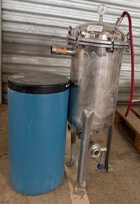 une photo d'un réservoir en acier inoxydable à côté d'un fût bleu