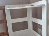 a white corner shelf with a wooden chair next to it